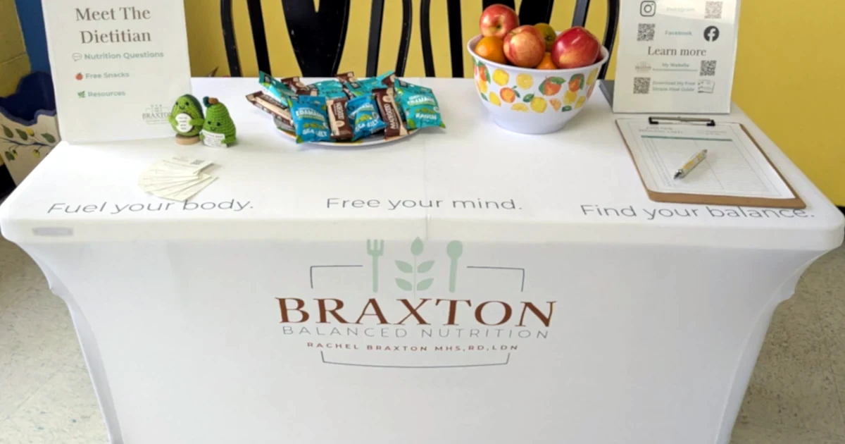 Braxton Balanced Nutrition event table with Fuel your body. Free your mind. Find your balance. written on the tablecloth and healthy snacks and business cards displayed.